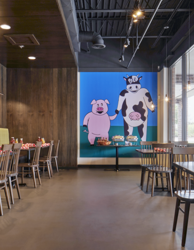 a room with tables and chairs and a painting of cows