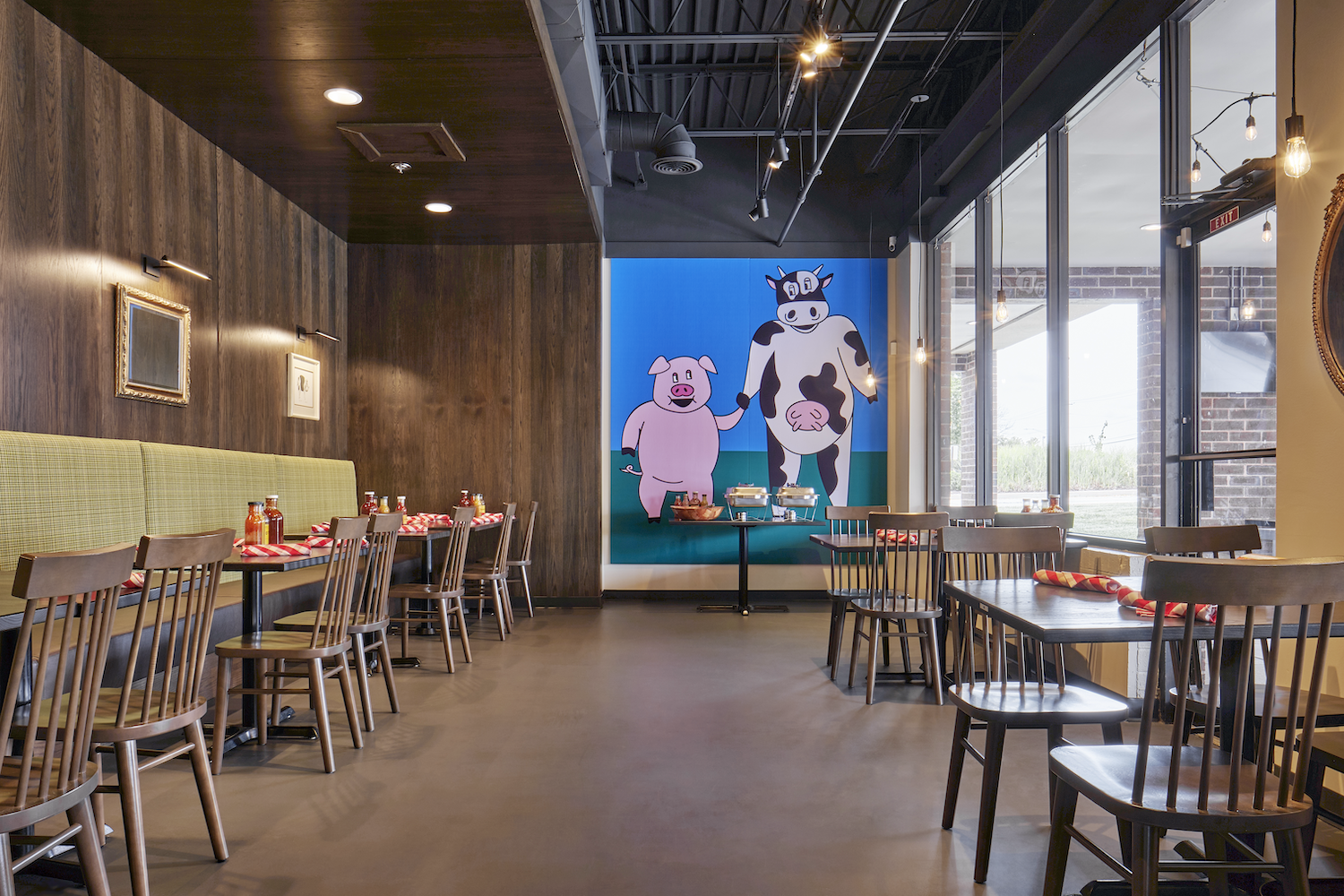 a room with tables and chairs and a painting of cows