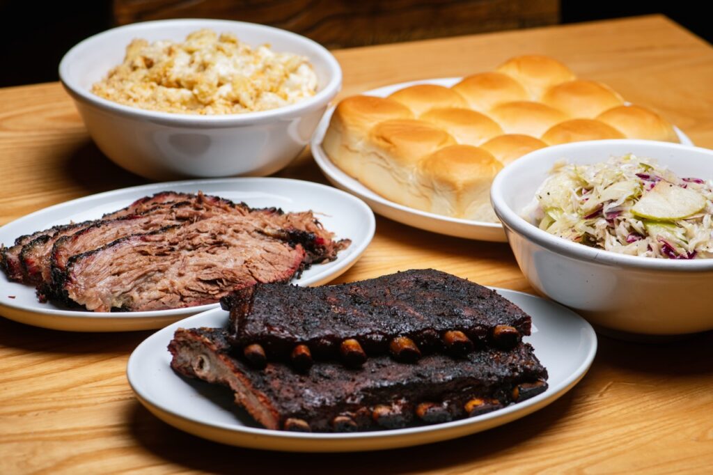 Salt + Smoke family meal deal with ribs, brisket, hawaiian rolls, and mac and cheese in frame
