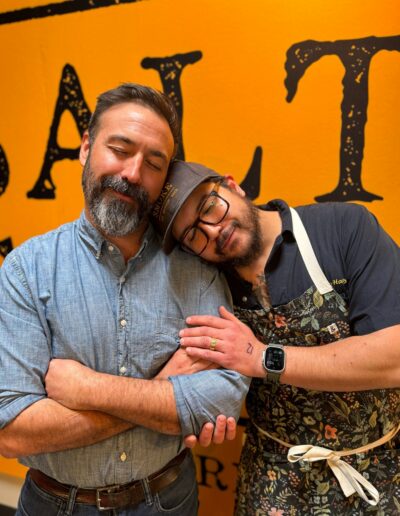 Tom and Haley Two men embracing in a kitchen