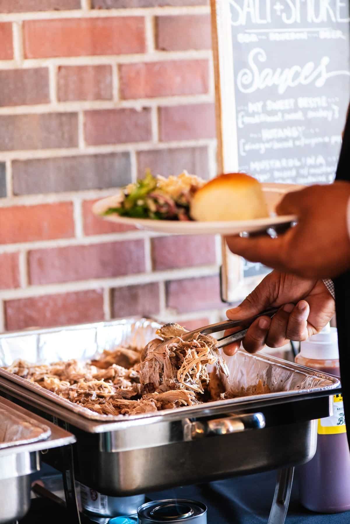 Guests serving themselves pulled pork from a catered buffet line