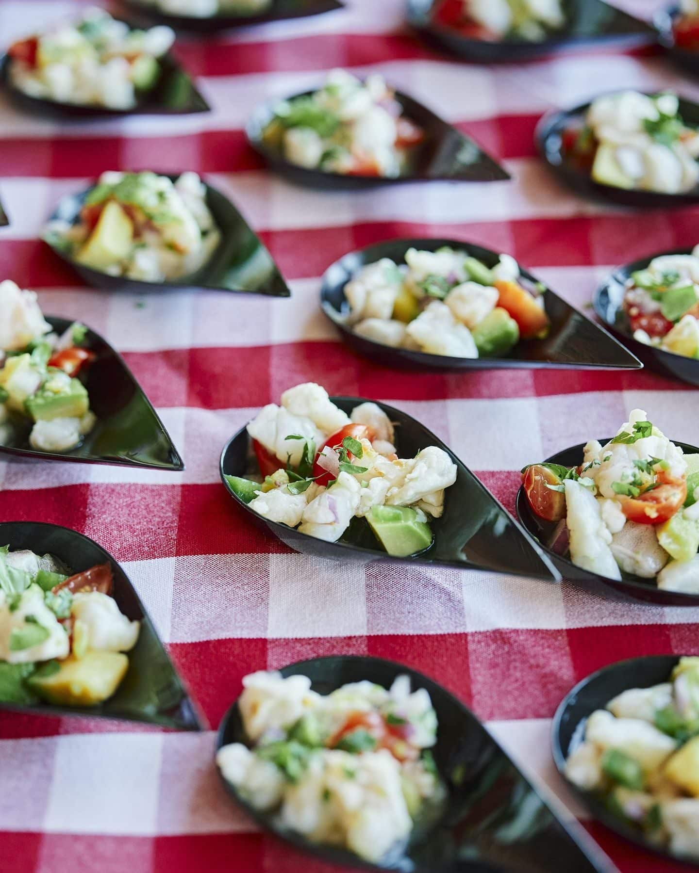 Appetizer spoons lined up on a red gingham tablecloth