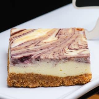 A square of berry swirl cheesecake on a graham cracker crust