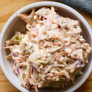 A bowl of creamy coleslaw with carrot and red cabbage