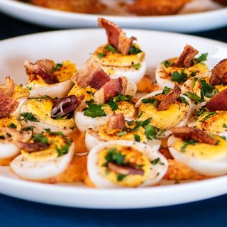 Deviled eggs topped with bacon, paprika and parsley