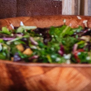 A wooden bowl of mixed green salad