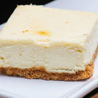 A square of New York style cheesecake on a graham cracker crust