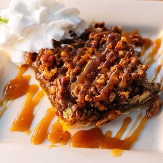 A brown butter pecan bar drizzled with caramel