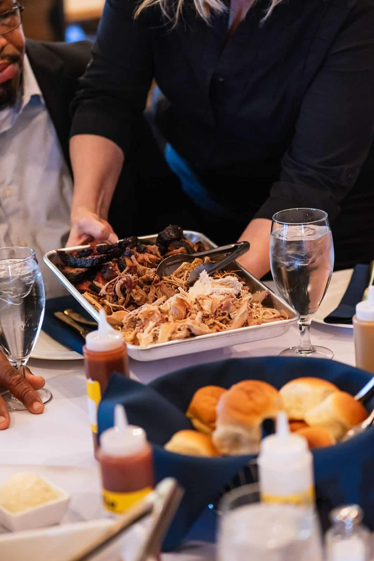 Parties + Events 2 A Salt + Smoke server setting out pulled pork, rolls and sauces at a party