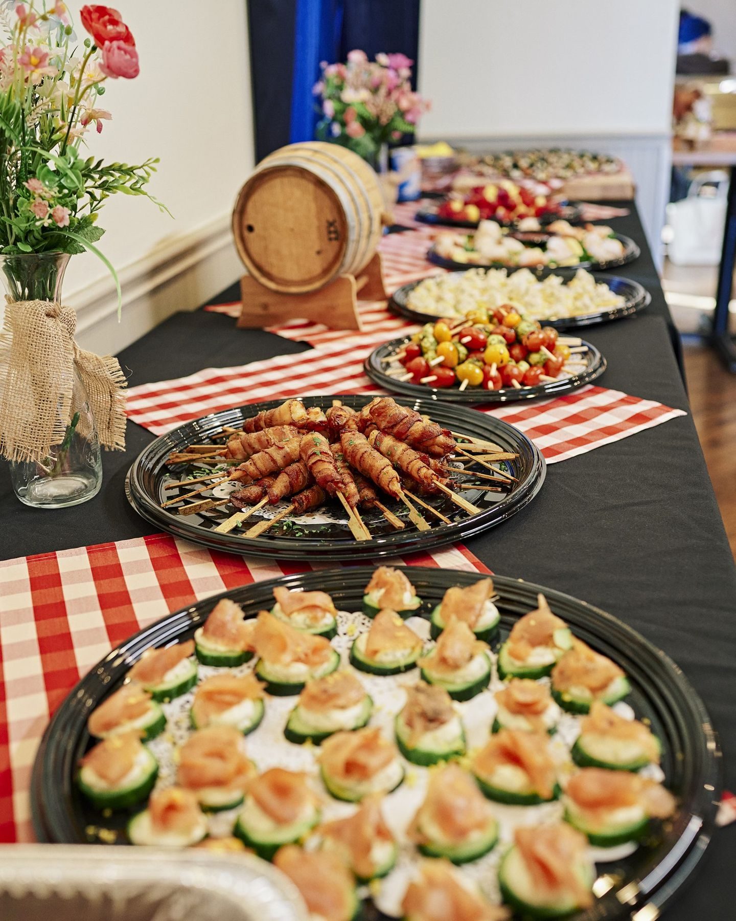 Weddings 1 A Salt + Smoke wedding buffet with flowers, a bourbon barrel and platters of appetizers on gingham