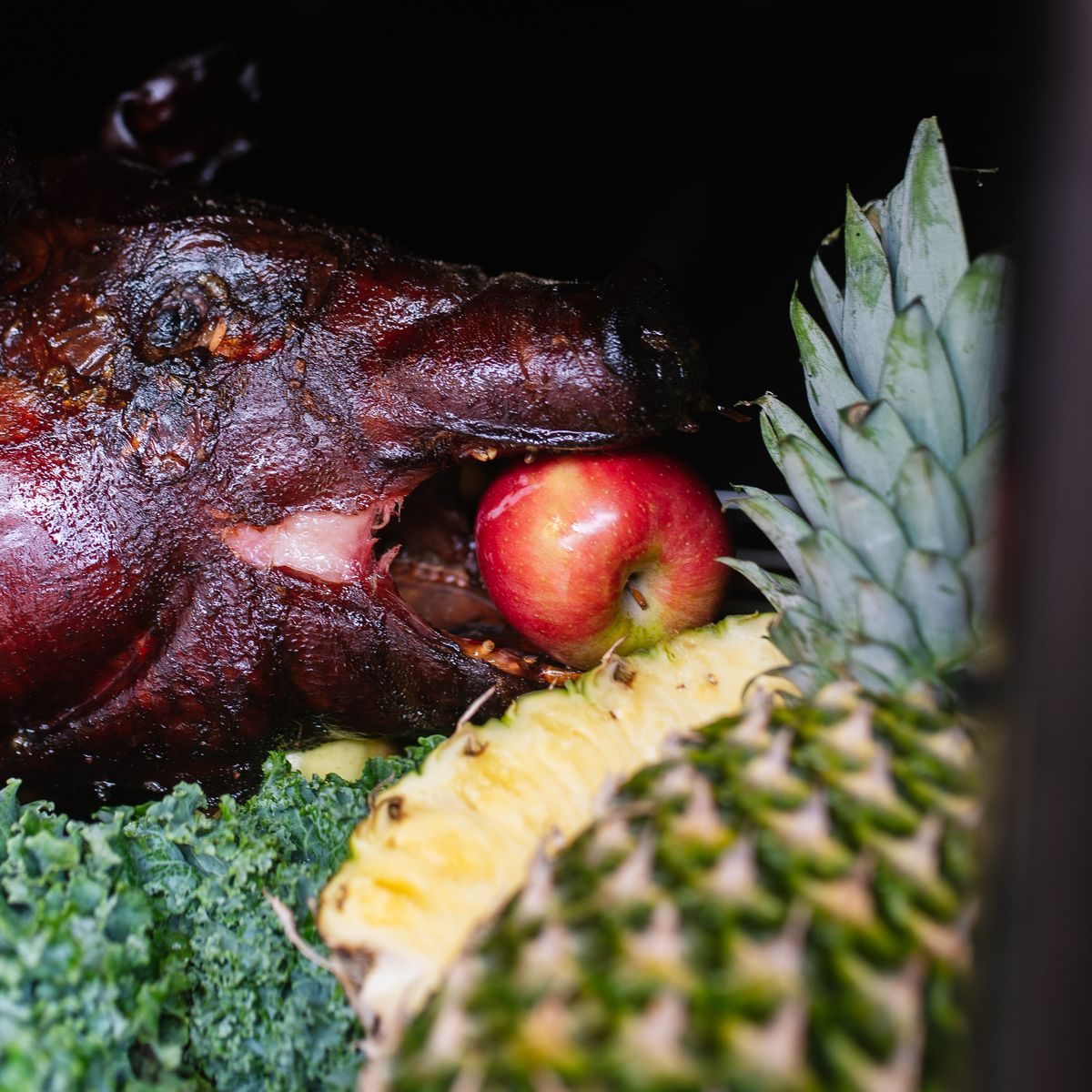 Catering 6 A whole smoked hog with an apple in its mouth, garnished with kale and pineapple