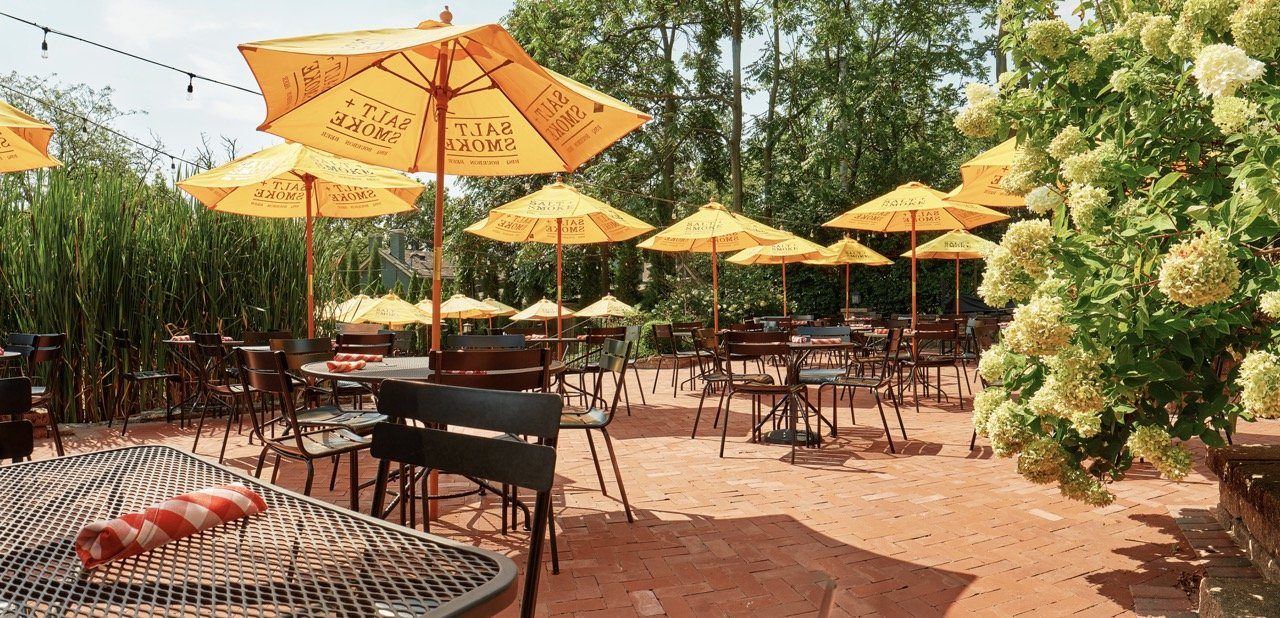 Book an event space 1 The Upper Tier patio in St. Charles with yellow umbrellas, string lights and hydrangeas